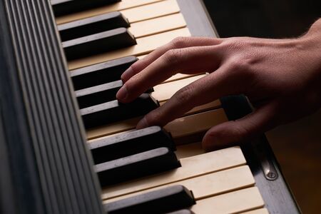 Hands playing on an old black pianoの写真素材
