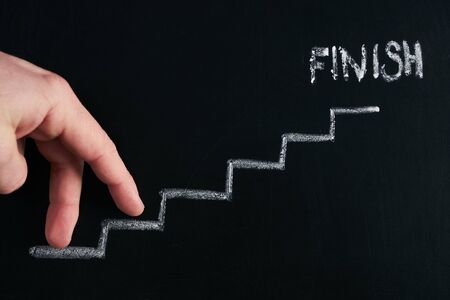 Hand walking on stairs with finish on chalkboard
