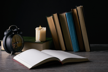 Blank notebook, books, alarm clock and candle on wooden table. Education, knowledge conceptの写真素材