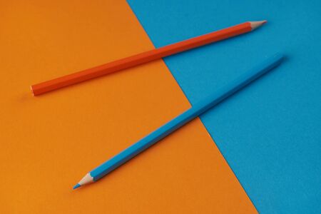 Colorful image of two pencils on orange and blue background.  Office, school supplyの写真素材