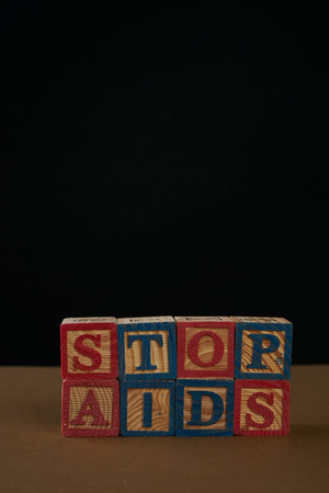 Stop AIDS on Cubes with letters on a table against black background. Copy spaceの写真素材