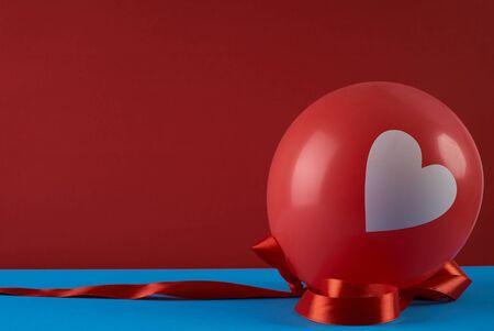 Red balloon with heart and ribbon against red background. Love card concept with copy space. Valentine's day themeの写真素材