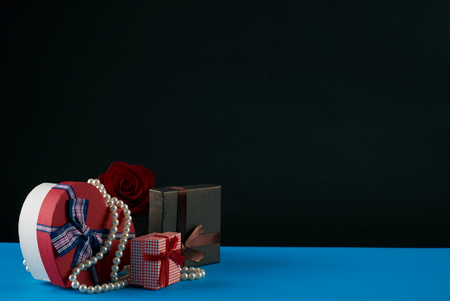 Gift boxes with rosebud and pearl necklace on dark background. Love present card concept with copy space. Valentine's day themeの写真素材