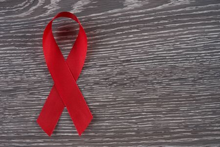 Red awareness ribbon on wooden background. Symbol of solidarity with people living with HIV AIDSの写真素材