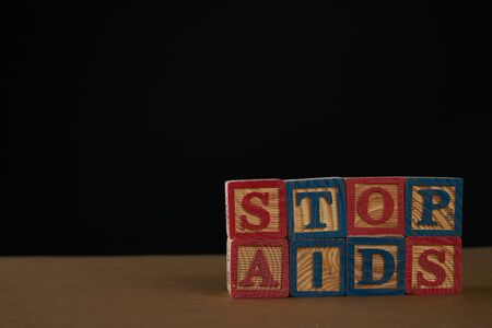 Stop AIDS on Cubes with letters on a table against black background. Copy spaceの写真素材
