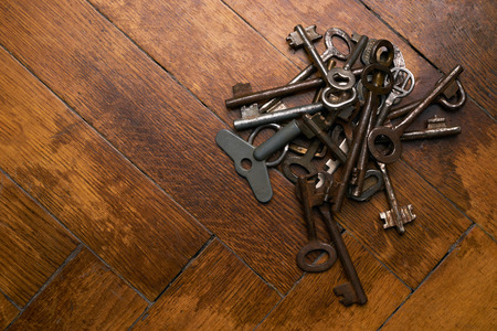 Top view of rusty old keys on brown wooden background. Copy spaceの写真素材