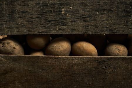 Raw potatoes food in an old wooden box.の写真素材