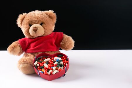 Teddy bear and heart shaped box with medicine and pills