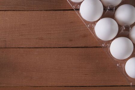 Eggs in egg tray on wooden background. Top view with copy space