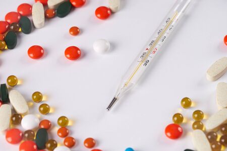 Thermometer and different colored medicine and types of pills. Medical health or drugs concept