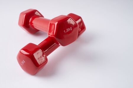 Closeup  of red dumbbells on white background. Fitness concept with copy spaceの写真素材