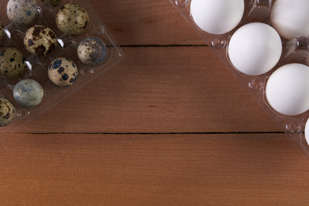 Chicken and quail eggs in trays on wooden table. close upの写真素材