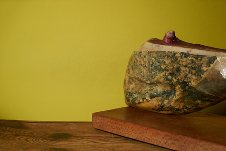 Smoked leg of lamb on wooden cutting board on yellow background with copy space.の写真素材