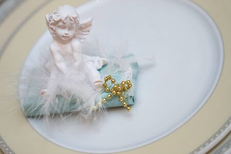 Close up photo of Festive table decoration with white plaster angel on plate.の写真素材