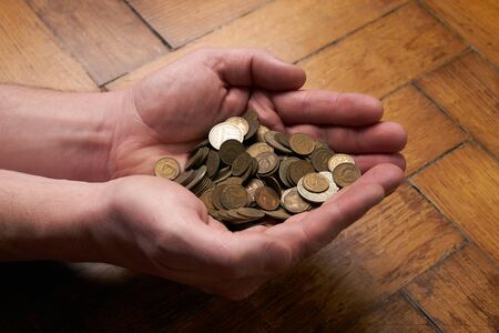 A man hand hold coins on old wooden background . Saving money or donation concept.Close up.の写真素材