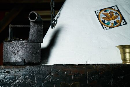 Closeup of rural clay stove and vintage antique iron &  bronze bowl on wooden dower chestの写真素材