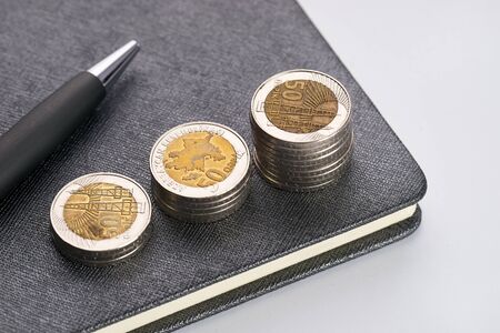 Pen with notebook and gold coins isolated on white background. The concept of a successful business.の写真素材
