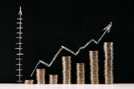 Business graph with arrow and coins showing profits and gainsの写真素材