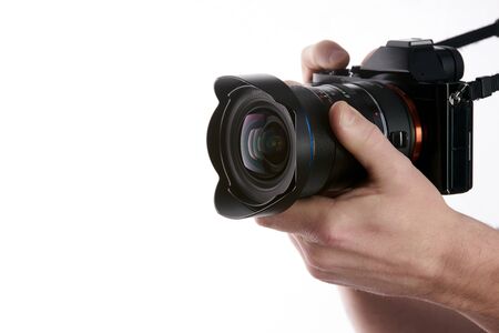 Camera in hand. Close-up of hand holding camera while isolated on white
