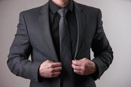 Portrait of stylish Businessman in black, trendy, modern and stylish suit holds a hand in pocket on isolated white backgroundの写真素材