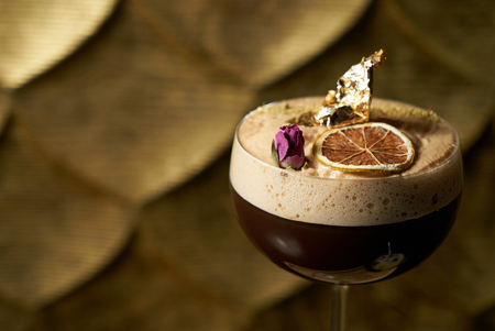Close-up of Fresh alcoholic cocktail with lime, mint garnish and and ice on black table and textured...