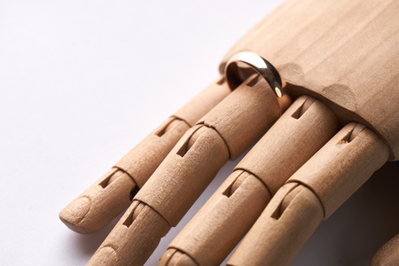 Prosthetic Wooden Hand with wedding ring on ring-finger isolated on white background. Bride and groom with golden wedding rings,marriage proposal.の写真素材