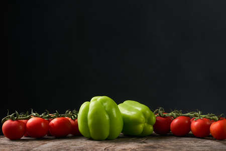 Close-up of vegan food and dishes. Tomatoes, bell peppers, aubergine on rustic wooden board isolated on black background. Healthy, clean eating concept. Vegan or gluten free diet. Space for text. Vegan dinnerの写真素材