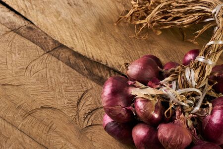 A lot of onions on wooden table. Heap of onions on a old rustic wooden board. Fresh red Onion on wooden background with copy space. Vegetables for healthy nutrition.の写真素材