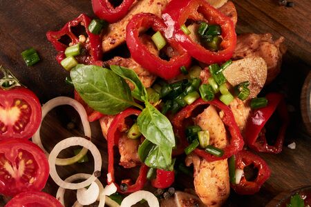 Close-up of fried chicken breast with baked vegetables on rustic wooden background.の写真素材