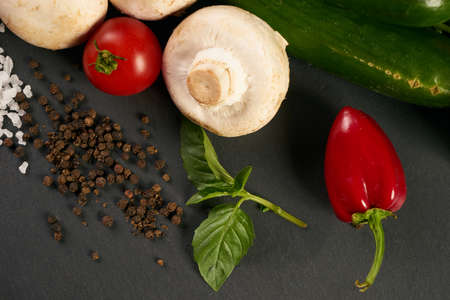 Fresh vegetable with leaves and seasoning spices on dark stone background. Healthy eating vegetarian food, detox concept.の写真素材