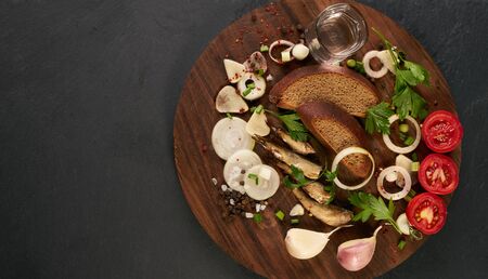 Cold glass of vodka with various traditional russian snack on wooden board over black stone background with copy space. Top view. The concept of national cuisine.の写真素材