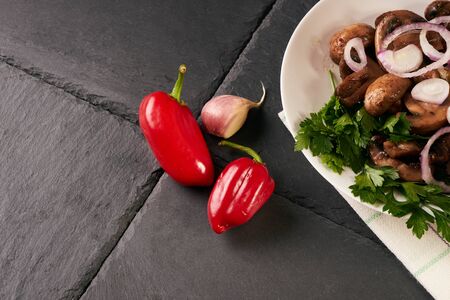 Cooked appetizing tasty fried mushrooms on white plate. Spring harvest of mushrooms cooked for a festive table. Healthy vegetarian food on a dark stone background.の写真素材