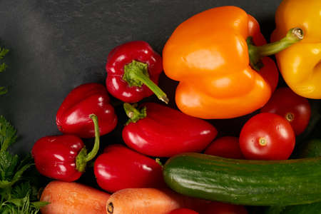 Fresh vegetables with greens on a black stone textured background. Healthy vegetarian eating.の写真素材