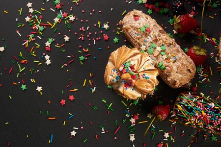 Dark cutting board with delicious eclairs and berries strawberries blackberries currants isolated on blackの写真素材