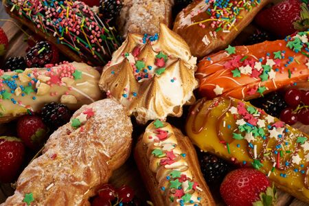 Group of french dessert Eclair on wooden round cutting board on black stone background with copy...