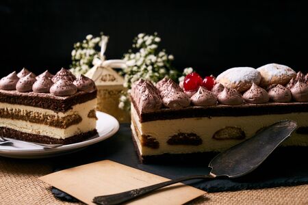 Homemade Christmas tiramisu cake with christmas decorations gift box, flowers and greeting card on black slate cake board.の写真素材