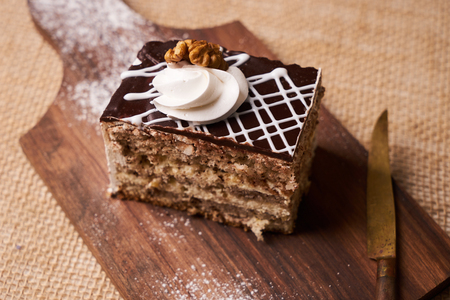 Slice of Chocolate cake with whipped cream and walnut on cutting board