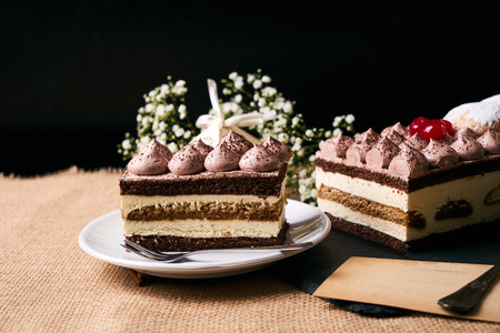 Homemade Christmas tiramisu cake with christmas decorations gift box, flowers and greeting card on black slate cake board.の写真素材