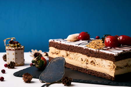 Christmas cake with fresh strawberries, whipped cream, chocolate and walnuts on black slate cake...
