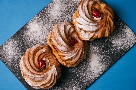 French dessert puff pastry profiteroles eclairs with custard cream, strawberry and powdered sugar on...