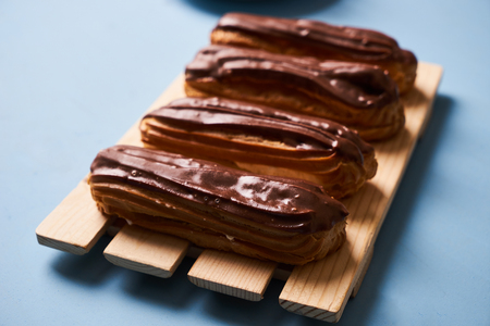 Delicious eclairs with chocolate frosting on the wooden table, top view, close-up.の写真素材