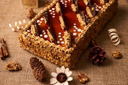 Delicious  biscuit cake with chocolate, walnut and whipped custard cream on textured background with Christmas decorationsの写真素材