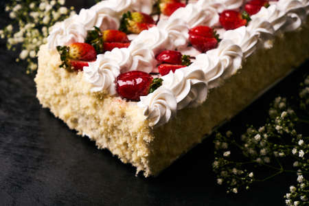 Strawberry cake with fresh strawberry, custard cream and biscuit on dark background, delicious sweet dessert foodの写真素材