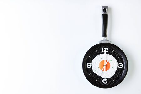 Breakfast with fried eggs on frying pan in shape of clock isolated on white background with copy...
