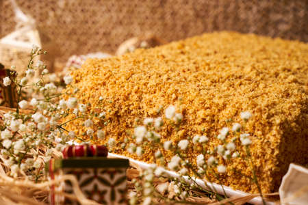 Delicious layered honey cake with sour cream on straw hay background with christmas decorationsの写真素材
