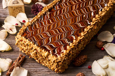 Peanut cake with chocolate and whipped custard cream on wooden table background with christmas...