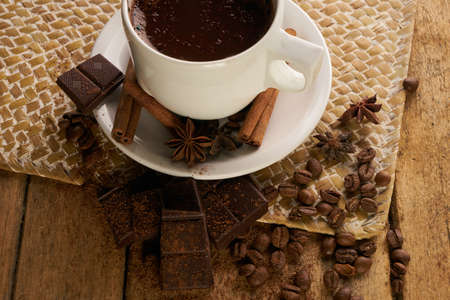 Cup of coffee with cinnamon sticks chocolate cocoa powder anise and coffee beans on old wooden...
