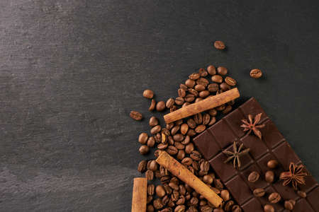 Aromatic set of chocolate bar, arabica coffee beans, anise and cinnamon on dark stone background...