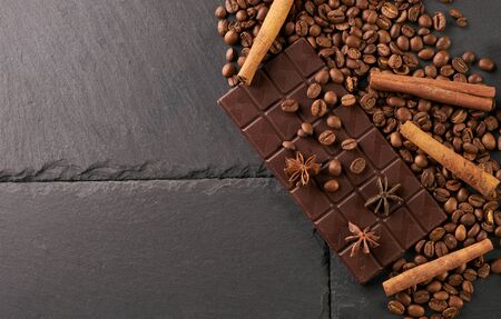 Top view of arabica coffee beans cinnamon star anise dark chocolate on black stone background with...