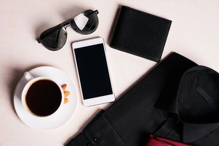 Men's fashion clothing with several accessories glasses, mobile phone, black leather walet and cup...